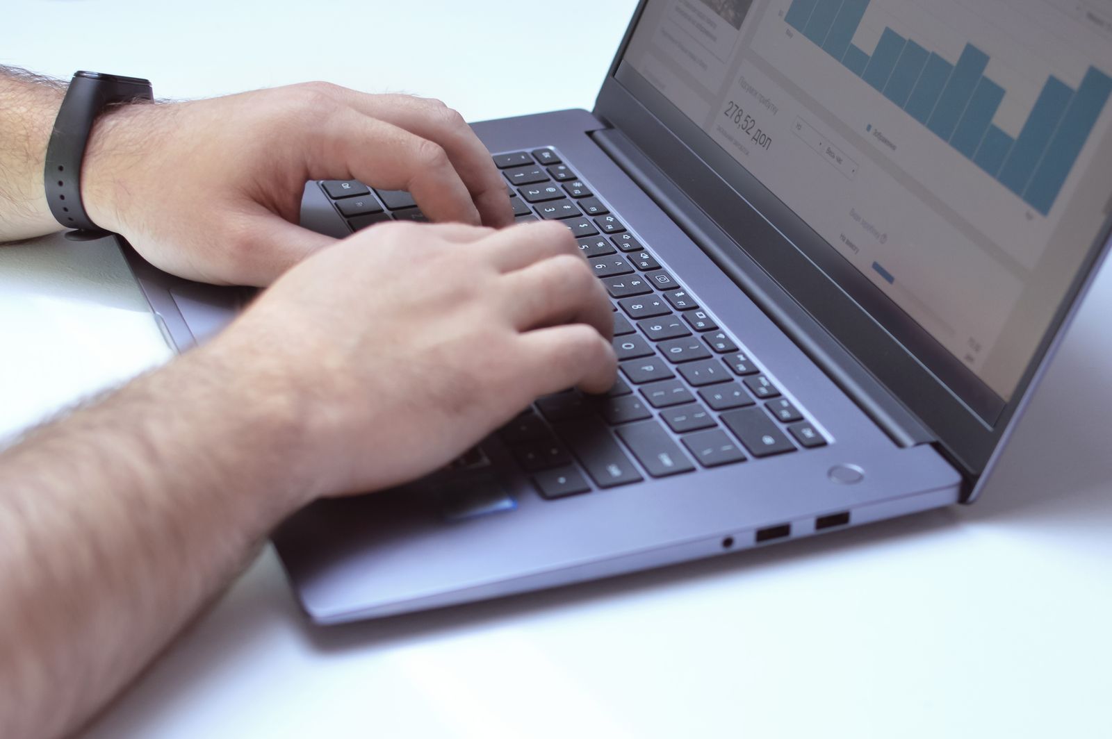 Handen aan een laptop met een overzicht van cijfers