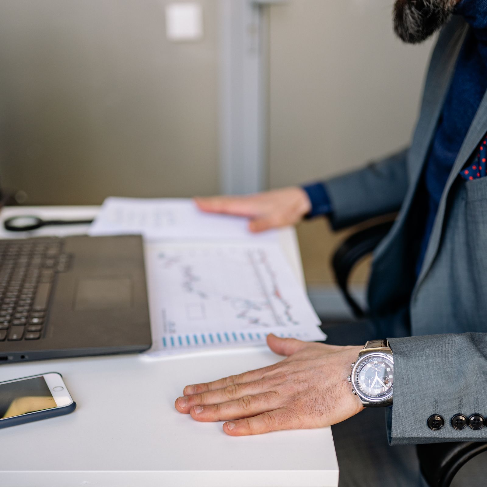 Handen bij rapportages en een laptop op een werktafel